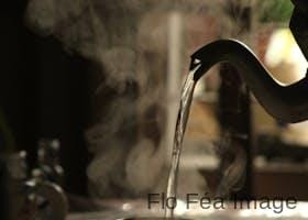 Warm indoor moment capturing steam from a teapot pouring into a mug, creating a cozy atmosphere.